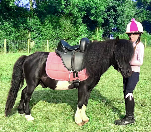 A horse wearing versatile kids saddle with a kid loving it
