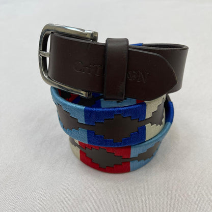 Colorful woven belt with a brown leather strap on a light gray background